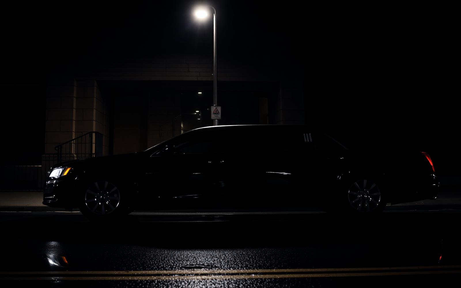 Schwarze Limousine bei Nacht unter Straßenlaterne